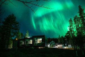 a house under the aurora borealis at night at Kuuru Tunturilaakso by Kide Hotel in Syöte