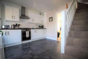 a kitchen with white cabinets and a staircase at Tides Reach in Walmer