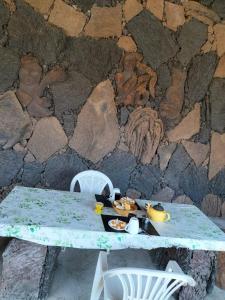 een tafel met eten naast een stenen muur bij Pensão Repouso Alegre Turismo e Aventura in Portela