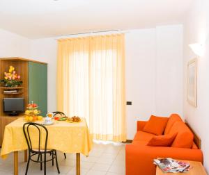 sala de estar con sofá naranja y mesa en Residence Il Monello, en Loano