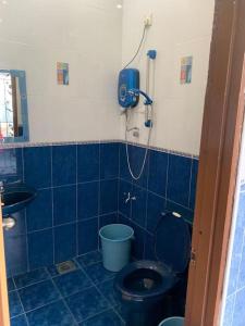 a blue tiled bathroom with a toilet and a shower at Home in Nilai in Nilai