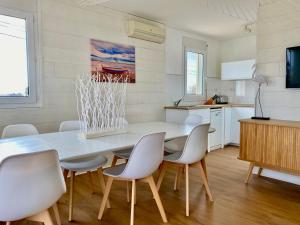 a dining room with a white table and chairs at Chalet L' Aliénor avec JACUZZI VUE MER 1ère ligne in Gruissan