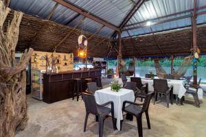 a restaurant with tables and chairs and a bar at EcoHotel La Fortuna 