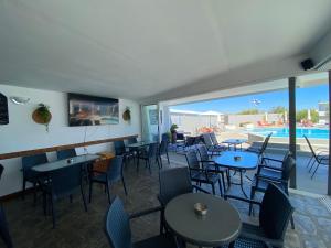 restauracja ze stołami i krzesłami oraz basen w obiekcie Family House Faliraki Studios Apartments w mieście Faliraki