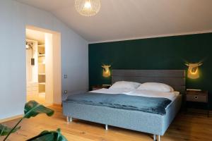 1 dormitorio con 1 cama grande y pared verde en Vive Diem, en Haus im Ennstal