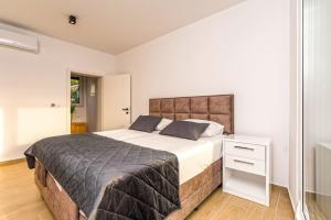 um quarto com uma cama grande e uma mesa de cabeceira branca em Villa Danijela, brand new villa with private pool em Stara Novalja