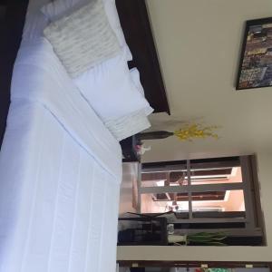 een bed met witte lakens en kussens in een kamer bij Villa Estela guesthouse in Bacong