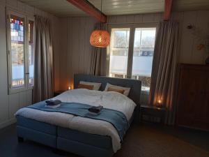 Un dormitorio con una cama azul con dos sombreros. en B&B Suyder Cogge en Hem