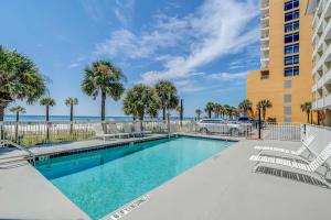 a swimming pool with palm trees and a building at Beach Tower Beachfront Hotel, a By The Sea Resort in Panama City Beach