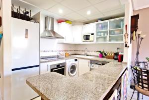a kitchen with white cabinets and a washer and dryer at Oasis Beach in Altea