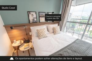 a bedroom with a white bed with a window at Charlie Vitrali Moema in Sao Paulo