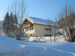 een huis is bedekt met sneeuw met bomen bij Ferienwohnung Kaiserblick in Sachrang