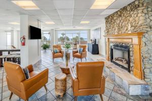 a lobby with chairs and a stone fireplace at Holiday Terrace Beachfront Hotel, a By The Sea Resort in Panama City Beach