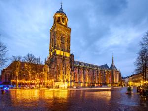 un grande edificio con torre dell'orologio di notte di Grand Boutique Hotel-Restaurant Huis Vermeer a Deventer