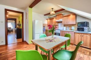 kuchnia ze stołem i zielonymi krzesłami w obiekcie Apartament przy Walowej w Łańcucie