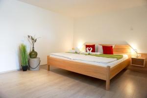 a bedroom with a bed with red and green pillows at Bergblick in Hopferau