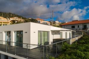 una casa bianca con balcone e sedie. di Casa Alan by Rent2u, Lda ad Arco da Calheta