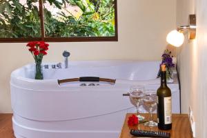 a bottle of wine sitting on a table next to a bath tub at Cabañas Armonía y Jardín de Orquídeas in Mindo