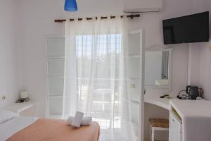 a bedroom with a large window with white curtains at HOTEL MOHITERO in Kamari
