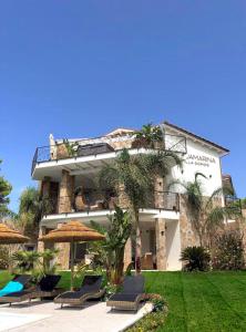 een gebouw met stoelen en parasols ervoor bij Villa Aquamarina Pintadera Rossa in Porto Pino