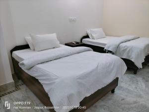 two beds in a room with white sheets and pillows at Casa Humana in Jaipur