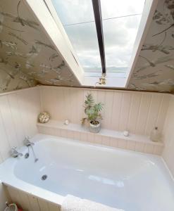 a bath tub in a bathroom with a skylight at Lovely 2 bed annexe with open plan living area in Salisbury