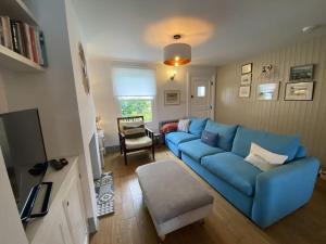 a living room with a blue couch and a tv at Mary's Cottage in Kingsdown