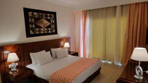 a bedroom with a bed and two lamps and a window at Oyster Bay Beach Resort - Luxury Serviced Condo in Marsa Alam City