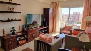 a living room with a flat screen tv and a couch at Oyster Bay Beach Resort - Luxury Serviced Condo in Marsa Alam City