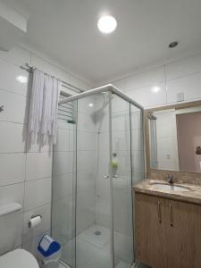 y baño con ducha, aseo y lavamanos. en Apartamento 2 dorm. em Bombas SC, en Bombinhas