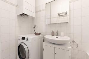 uma casa de banho branca com uma máquina de lavar roupa e um lavatório em Cozy Home Vienna em Viena