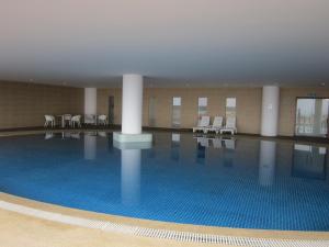 a large swimming pool with white chairs and tables at WenCozy 118 Vacation Home in George Town
