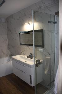 a bathroom with a sink and a glass shower at Apartamenty Twoje Mikołajki in Mikołajki
