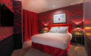 Schlafzimmer mit einem großen Bett mit roten Wänden in der Unterkunft Hôtel La Parizienne in Paris