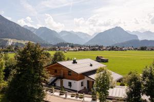 ein Haus auf einem Feld mit Bergen im Hintergrund in der Unterkunft Alpine Lifestyle Lodge in Oberstdorf