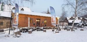 a building with tables and chairs in the snow at Apartmán Konírna in Harrachov
