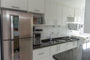 cocina con armarios blancos y nevera de acero inoxidable en Apto com Wi Fi e otima localizacao em Curitiba PR, en Curitiba