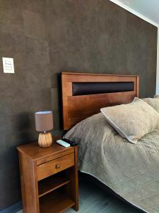 um quarto com uma cama e uma mesa de cabeceira com um candeeiro em Moderna Cabaña con tinaja caliente em Pirque