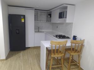 a kitchen with two chairs and a black refrigerator at Hermosa casa ideal para el descanso in Rionegro