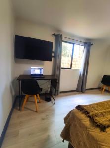 Schlafzimmer mit einem Schreibtisch, einem Laptop und einem Fenster in der Unterkunft Moderna Cabaña con tinaja caliente in Pirque
