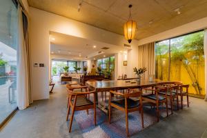 uma sala de jantar com uma mesa de madeira e cadeiras em Akala Villa Hoi An em Hoi An