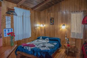 ein Schlafzimmer mit einem Bett in einem Zimmer mit Holzwänden in der Unterkunft Cabañas Armonía y Jardín de Orquídeas in Mindo