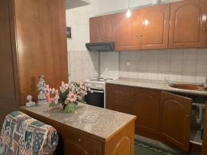 una cocina con armarios de madera y una encimera con flores. en Διαμέρισμα στο κέντρο του χωριού en Kotrónion