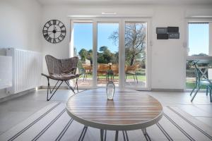 sala de estar con mesa y reloj en la pared en La Maison Des Lys YourHostHelper en Gujan-Mestras