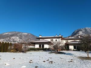 une maison dans la neige avec des montagnes en arrière-plan dans l'établissement casa Rosalba, à Strigno