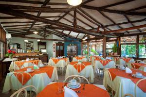 un restaurante con mesas y sillas de color naranja y blanco en Pousada Estalagem Vila Tania en Itaúnas