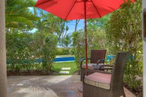 Un patio con una mesa y una sombrilla roja. en Sapphire Beach Condos, en Christ Church