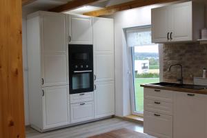 cocina con armarios blancos, fogones y ventana en Ferienwohnung Stefanko, en Bernau