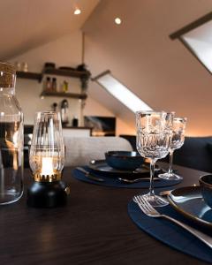 a table with two wine glasses and plates on it at Scenic Penthouse - Ocean view & skylight windows in Siglufjörður
