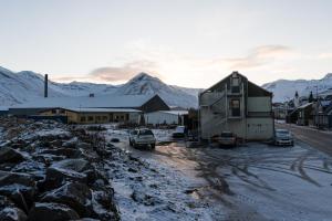 una casa con coches aparcados frente a una montaña en Scenic Penthouse - Ocean view & skylight windows en Siglufjörður